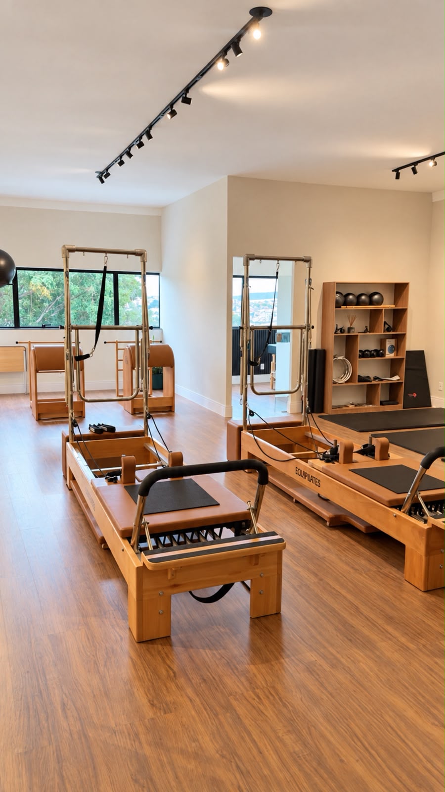 Interior do SUNT Studio com aparelhos de Pilates em madeira, iluminação acolhedora e grandes janelas.